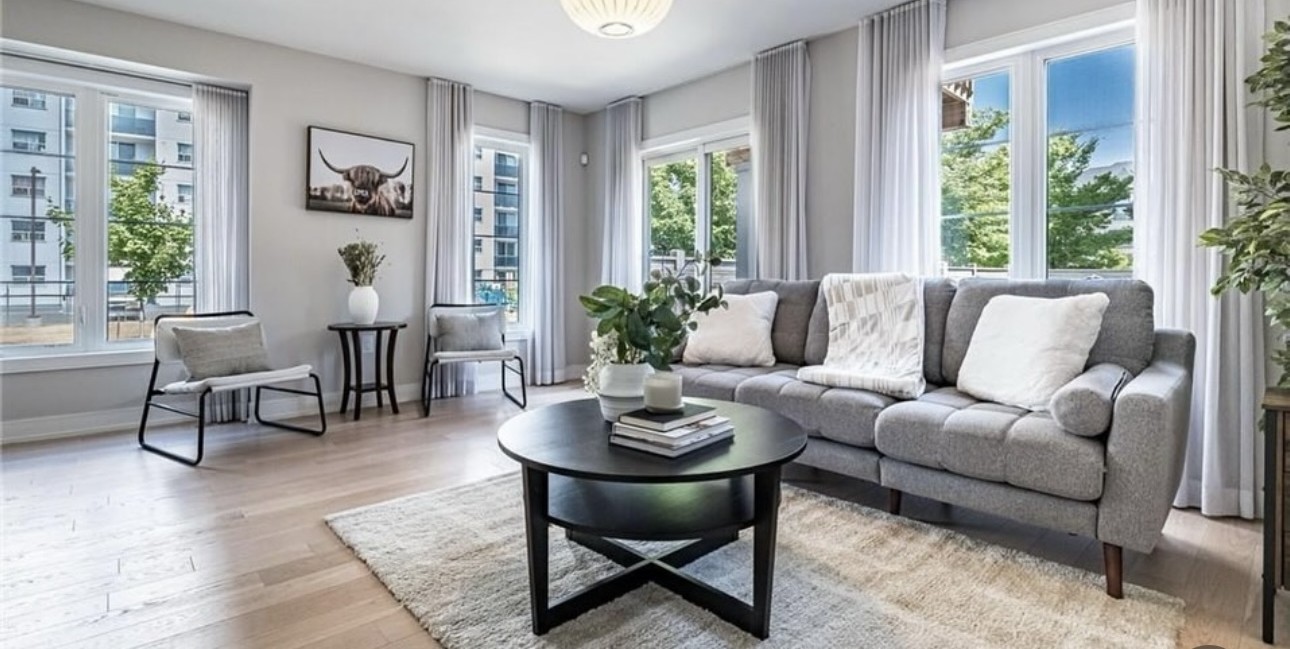 The townhouse living room with a grey sofa, round black coffee table and framed artwork